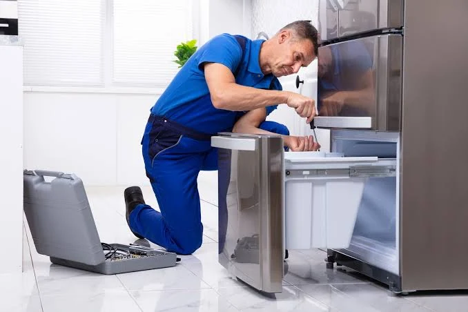Appliance repair technician servicing an open refrigerator